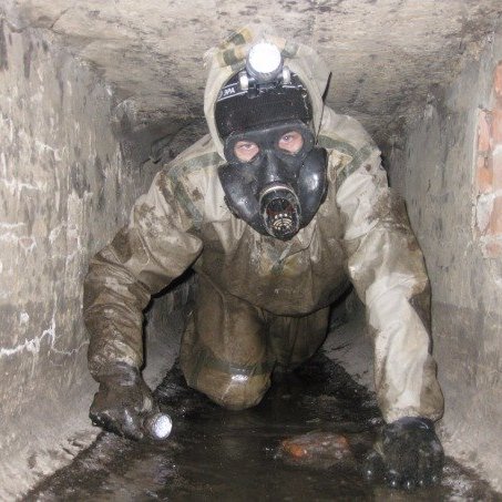 Диггер в туннеле в защитном костюме с налобным фонариком в маске